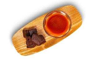 Top view pile of crispy brownie chocolate cube and a glass of tomato juice in wooden tray isolated on white background with clipping path. photo