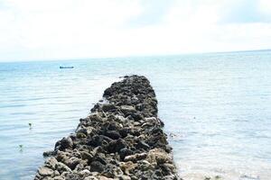 a serene coastal scene with a stone pathway extending into the calm photo