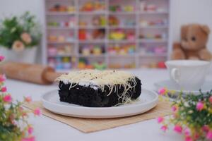 A piece of black cake topped with shredded cheese photo