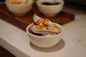 Chocolate ice cream with colorful candies on the white background. photo