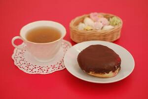 donut and cup of tea on the red table photo