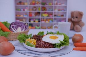 A vibrant meal consisting of red rice, meat, corn, carrots, lettuce, and a sunny side up egg photo