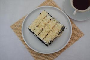 A piece of black cake topped with shredded cheese photo
