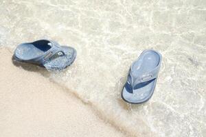 flip flops on the sand at the beach with sea background photo