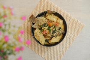Fried fish with curry in a bowl on a wooden table. photo
