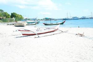 Quiet Beach with Traditional Boat and Clear Blue Waters photo