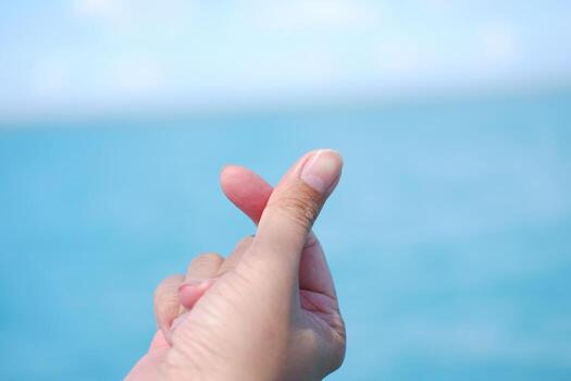 Hands forming a heart shape with the sea in the background. photo