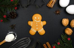 Gingerbread man, Christmas decor and ingredients for baking on a black background. Christmas baking concept. Flatlay composition. Top view. photo