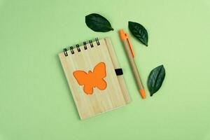 A notebook and pen made of eco friendly materials on a green background. Top view. Flatlay composition. Copy space. photo