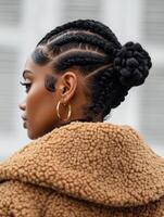 Side profile of a woman with braided cornrows styled into a low bun, featuring baby hairs and a fashionable look. photo