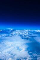 Aerial view from airplane window above green ground. View from the airplane window with beautiful clouds at sunrise. Earth and sky as seen through window of an airplane. photo