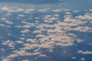 Aerial view from airplane window above green ground. View from the airplane window with beautiful clouds at sunrise. Earth and sky as seen through window of an airplane. photo