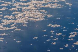 Aerial view from airplane window above green ground. View from the airplane window with beautiful clouds at sunrise. Earth and sky as seen through window of an airplane. photo