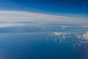 Aerial view from airplane window above green ground. View from the airplane window with beautiful clouds at sunrise. Earth and sky as seen through window of an airplane. photo