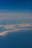 Aerial view from airplane window above green ground. View from the airplane window with beautiful clouds at sunrise. Earth and sky as seen through window of an airplane. photo