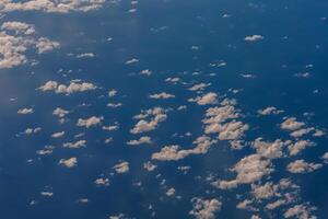 Aerial view from airplane window above green ground. View from the airplane window with beautiful clouds at sunrise. Earth and sky as seen through window of an airplane. photo
