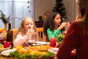 Grandfather, parents, and the teenage girls are all having dinner together at home on Christmas night photo
