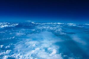 Aerial view from airplane window above green ground. View from the airplane window with beautiful clouds at sunrise. Earth and sky as seen through window of an airplane. photo