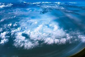 Aerial view from airplane window above green ground. View from the airplane window with beautiful clouds at sunrise. Earth and sky as seen through window of an airplane. photo