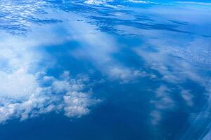 Aerial view from airplane window above green ground. View from the airplane window with beautiful clouds at sunrise. Earth and sky as seen through window of an airplane. photo