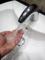 photo tutorial on washing hands with clean water in the sink.