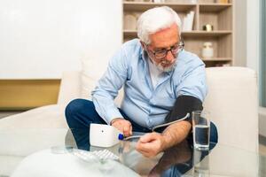 Hypertension problem in senior age. Old man measuring blood pressure with tonometer at home. Senior man have health problem making self checkup. Headache treatment of hypertension hypotension photo