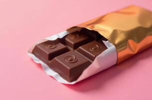 Luxury chocolate bar wrapped in gold foil on pink background photo