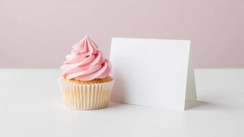 Pink frosted cupcake with blank card on pastel background for celebrations and events. valentine's day photo