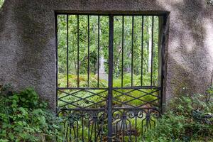 Rustic iron gate revealing a hidden cross among lush greenery, capturing peaceful and spiritual charm photo