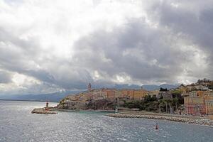 Panoramic view of Bastia Corsica from the sea with colorful buildings under dramatic cloudy skies photo