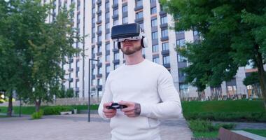 A man wearing a virtual reality headset is standing in front of a building video
