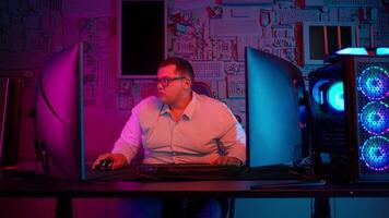 A man sitting at a desk with a computer and a monitor video