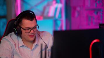 A man wearing headphones and a headset in front of a computer video