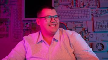 A man in glasses sitting at a desk with a computer video