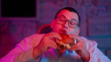 A man eating a hamburger in front of a computer screen video
