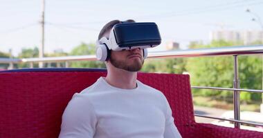 A man wearing a virtual reality headset sitting on a bench video