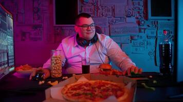 A man sitting at a table with pizza and a computer video