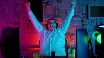 A man in a white shirt with his arms up in front of a computer video