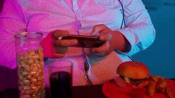 A man holding a cell phone and eating a burger video