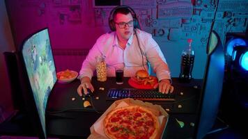 A man in glasses sitting at a desk with a pizza and a computer video