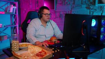A man in glasses sitting at a desk with a pizza and a computer video