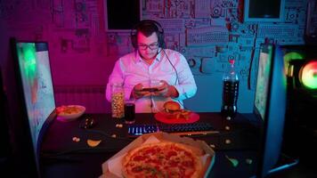 A man in glasses sitting at a desk with a pizza and a computer video