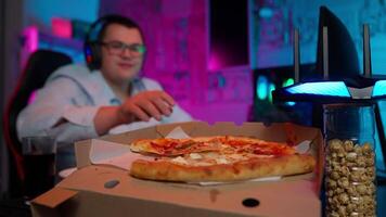 A man sitting at a table with a pizza and a computer video