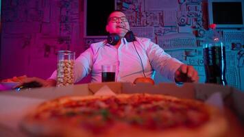 A man in a white shirt and headphones sitting at a table with a pizza video