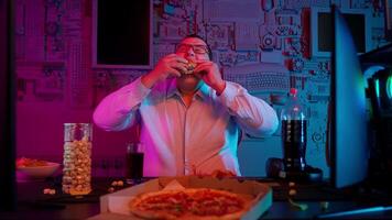 A man eating pizza and watching a movie video