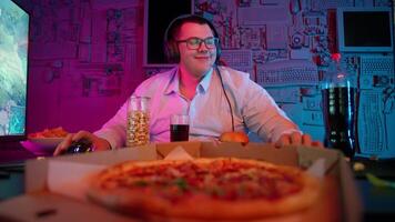 A man in glasses sitting at a table with a pizza video