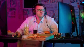 A man in glasses sitting at a desk with a pizza and a computer video