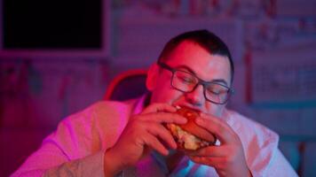 A man eating a hamburger in front of a computer screen video