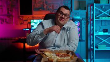 A man in glasses sitting at a table with a pizza video