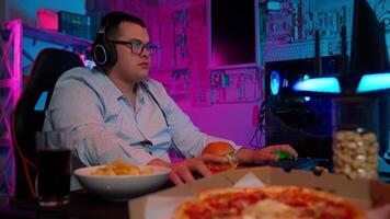 A man in glasses playing games with pizza and chips video